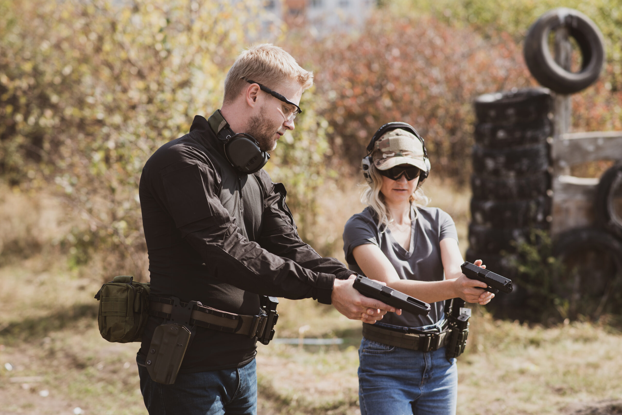 A woman learns to shoot a pistol at a shooting range with an instructor